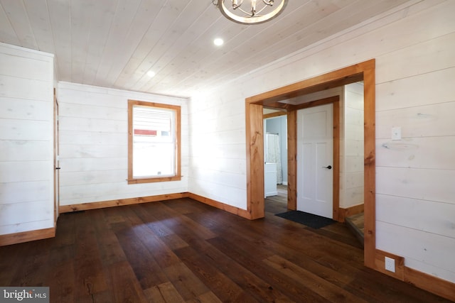 empty room with dark wood-type flooring, wood ceiling, and baseboards