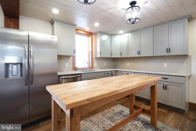 kitchen featuring dark wood finished floors, decorative backsplash, appliances with stainless steel finishes, wooden ceiling, and a sink