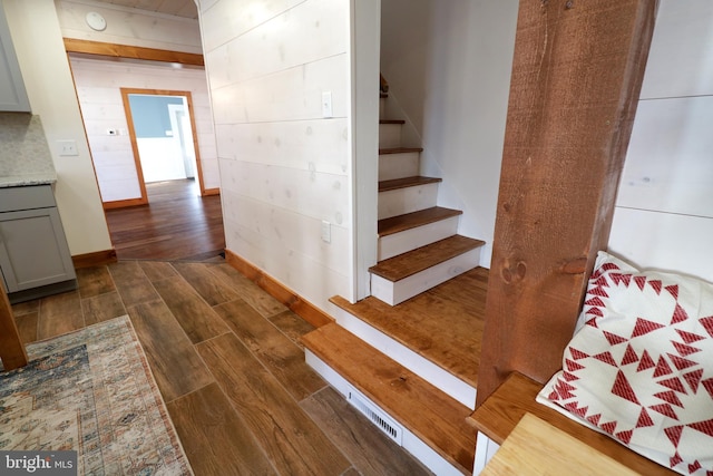 staircase featuring wooden walls and wood finished floors