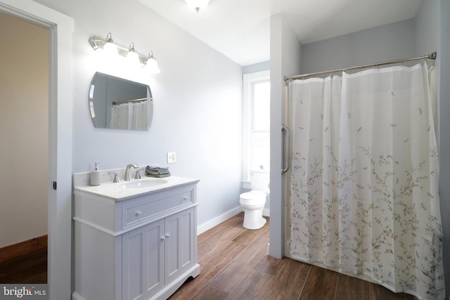 bathroom with a shower with curtain, toilet, wood finished floors, baseboards, and vanity