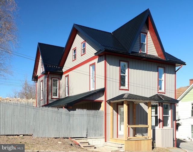 view of front of house featuring metal roof, a standing seam roof, and fence