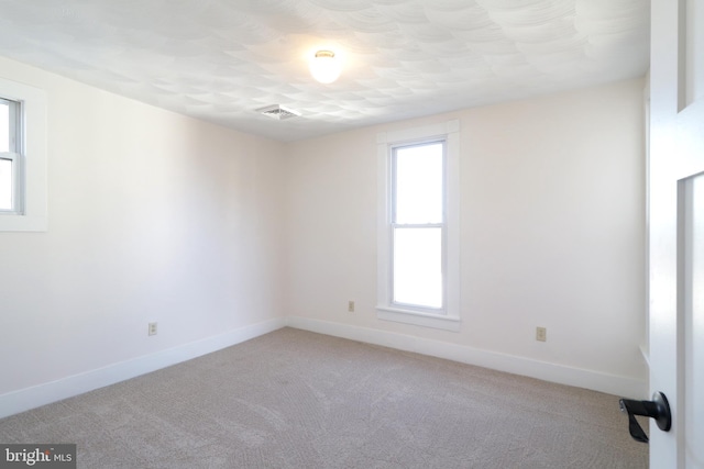 empty room with visible vents, baseboards, and light carpet