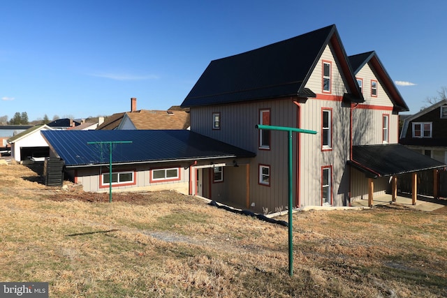 rear view of house featuring metal roof and a lawn