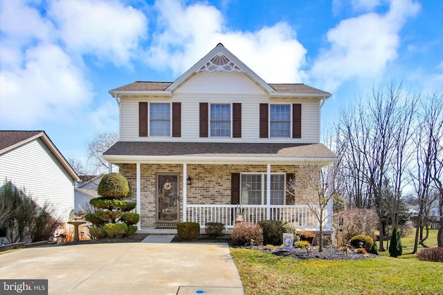 view of front of property with a porch, brick siding, and a front lawn