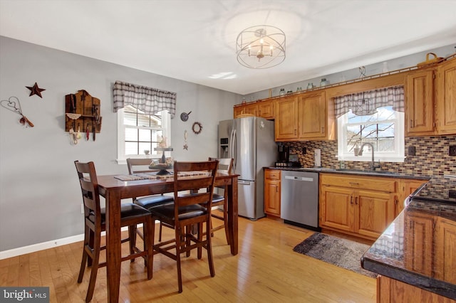 kitchen featuring decorative backsplash, dark countertops, appliances with stainless steel finishes, and a sink