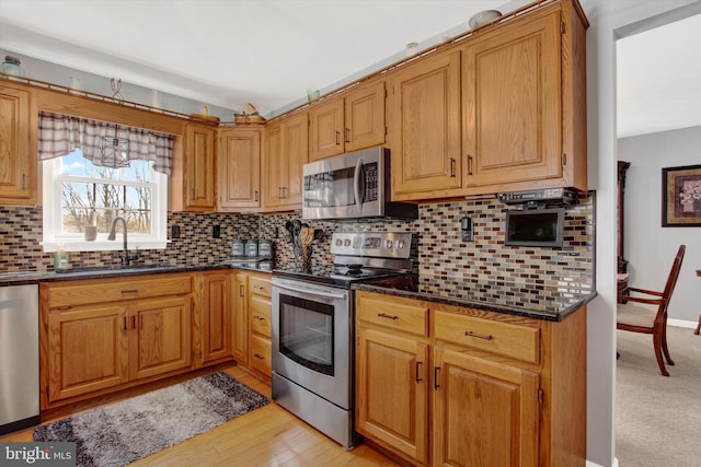 kitchen with a sink, decorative backsplash, appliances with stainless steel finishes, and dark stone countertops