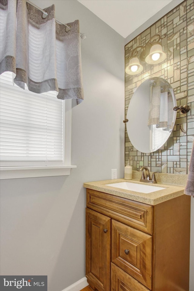 bathroom with decorative backsplash, vanity, and baseboards