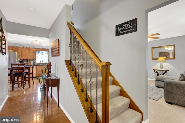 stairs featuring baseboards, ceiling fan, and hardwood / wood-style flooring