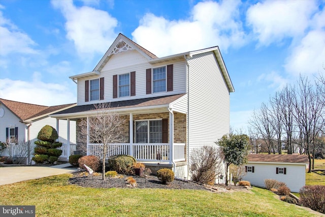 view of front of property with brick siding, a porch, driveway, and a front lawn