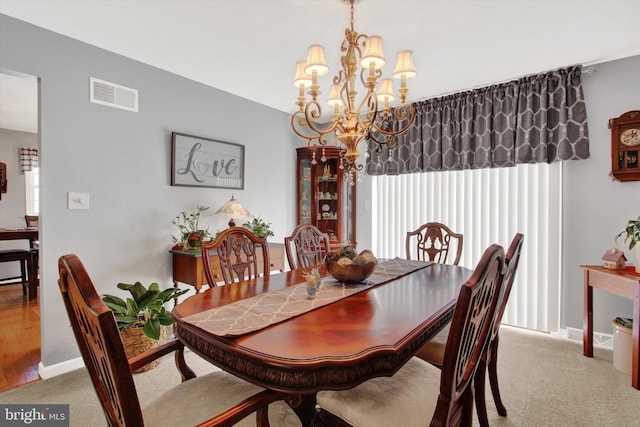 dining space featuring an inviting chandelier, carpet, visible vents, and baseboards