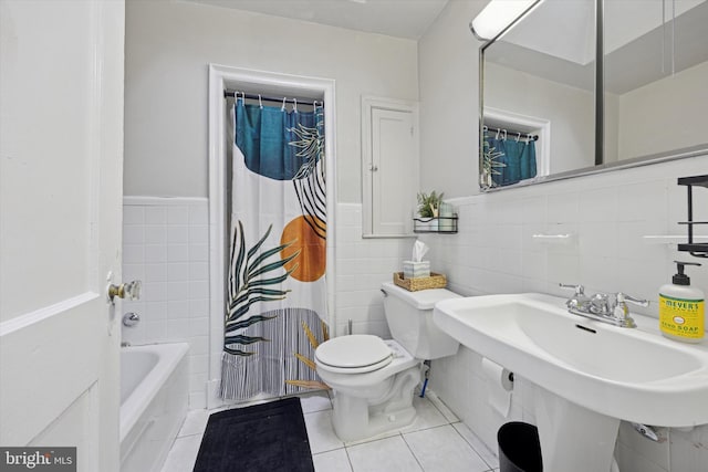 full bath with a wainscoted wall, toilet, a sink, tile walls, and tile patterned flooring