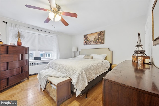 bedroom with light wood-type flooring, radiator heating unit, and a ceiling fan