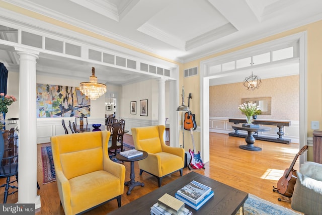 living area with visible vents, wood finished floors, wainscoting, and ornate columns