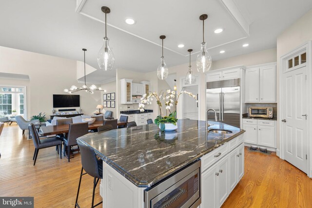 kitchen featuring a sink, built in appliances, white cabinets, and light wood finished floors