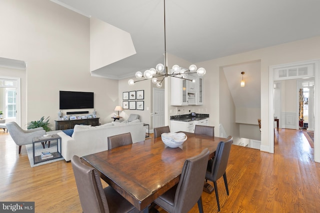 dining area featuring a notable chandelier, light wood-style floors, and crown molding