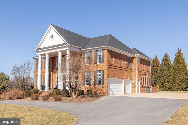 greek revival house with brick siding, central AC, roof with shingles, a garage, and driveway