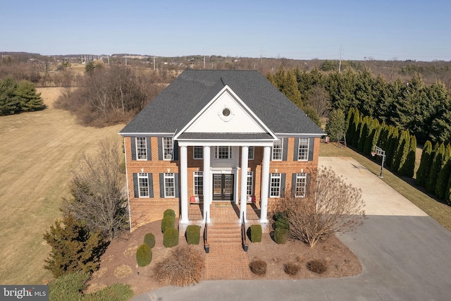 neoclassical / greek revival house with concrete driveway, french doors, and brick siding