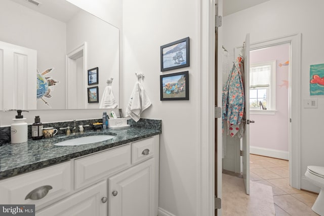 bathroom featuring tile patterned flooring, toilet, vanity, and baseboards