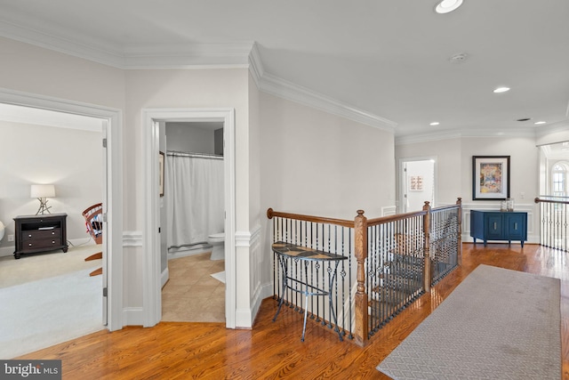 hall with wood finished floors, an upstairs landing, ornamental molding, and recessed lighting