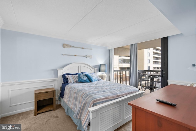 bedroom featuring light colored carpet, crown molding, wainscoting, and access to outside