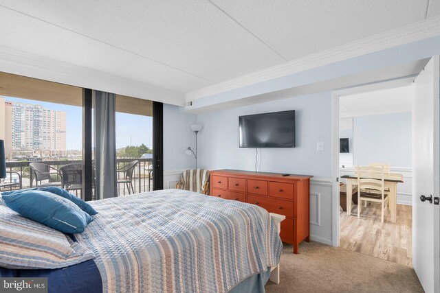 carpeted bedroom featuring access to exterior, a wainscoted wall, a wall of windows, and ornamental molding