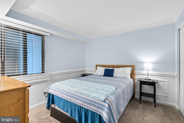 carpeted bedroom with ornamental molding and wainscoting