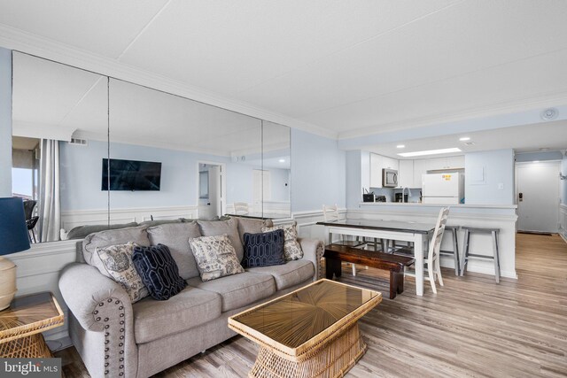 living area featuring crown molding, visible vents, and light wood-type flooring