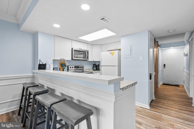 kitchen featuring visible vents, a kitchen breakfast bar, stainless steel appliances, a peninsula, and light countertops