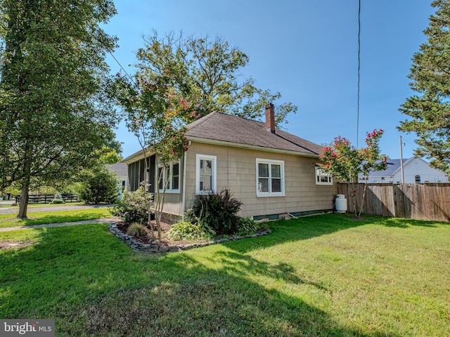 view of side of home with a yard, fence, and a chimney