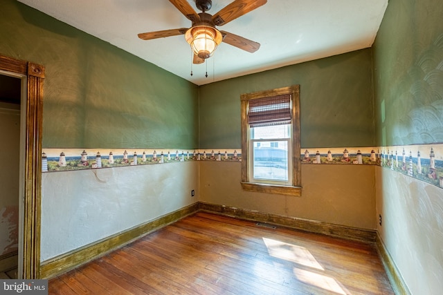 unfurnished room with hardwood / wood-style flooring, a ceiling fan, and baseboards