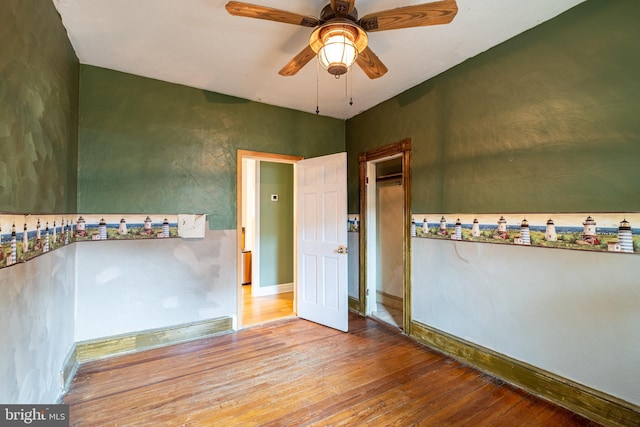 empty room featuring hardwood / wood-style floors, baseboards, and ceiling fan