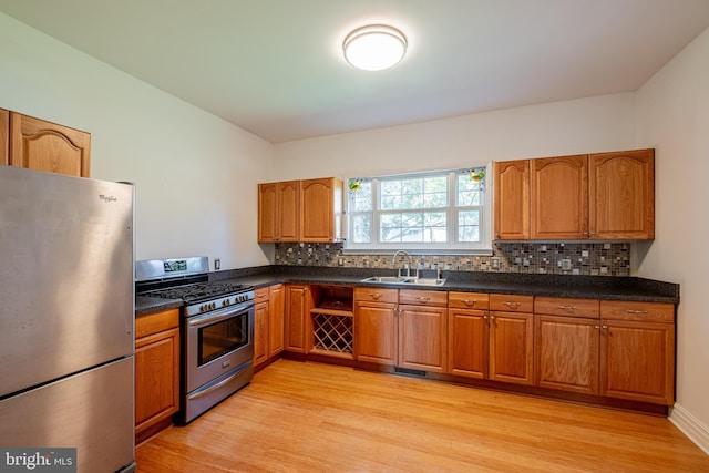 kitchen featuring decorative backsplash, appliances with stainless steel finishes, light wood-style floors, brown cabinetry, and a sink