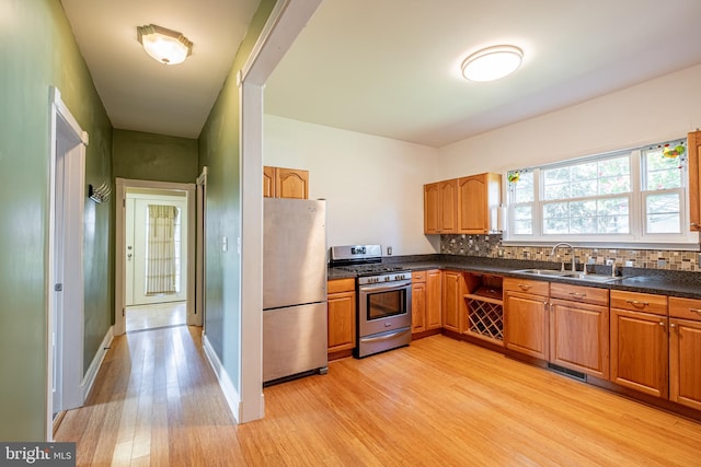 kitchen featuring a sink, dark countertops, light wood-style flooring, and stainless steel appliances