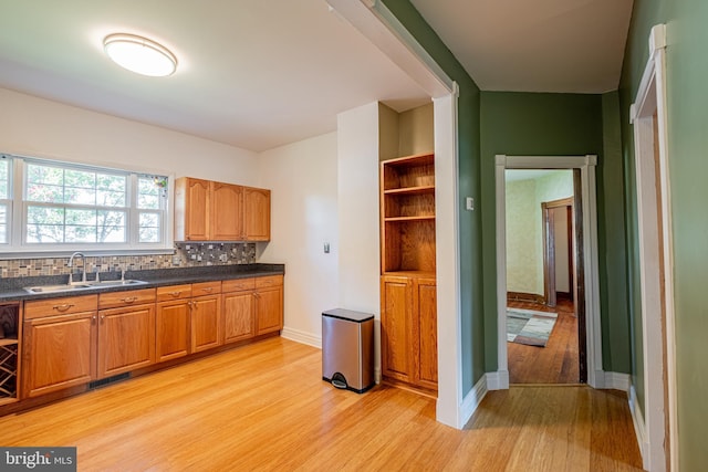 kitchen with light wood finished floors, dark countertops, visible vents, decorative backsplash, and a sink