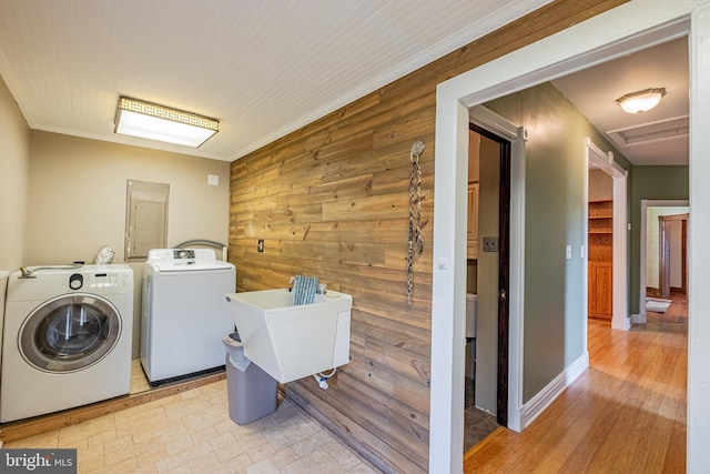 washroom with washing machine and clothes dryer, stone finish flooring, wood walls, laundry area, and a sink