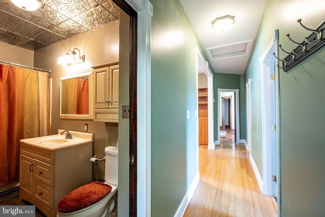 corridor with an ornate ceiling, attic access, baseboards, and a sink