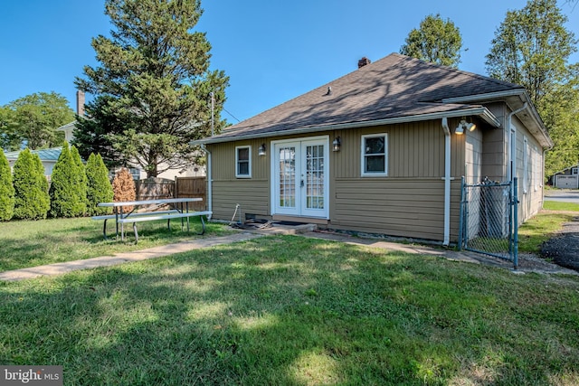 rear view of house with a trampoline, french doors, fence, and a yard