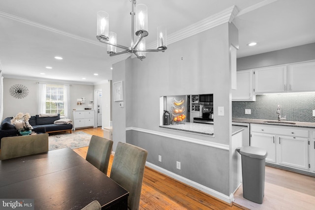 dining space with light wood finished floors, crown molding, baseboards, recessed lighting, and a notable chandelier