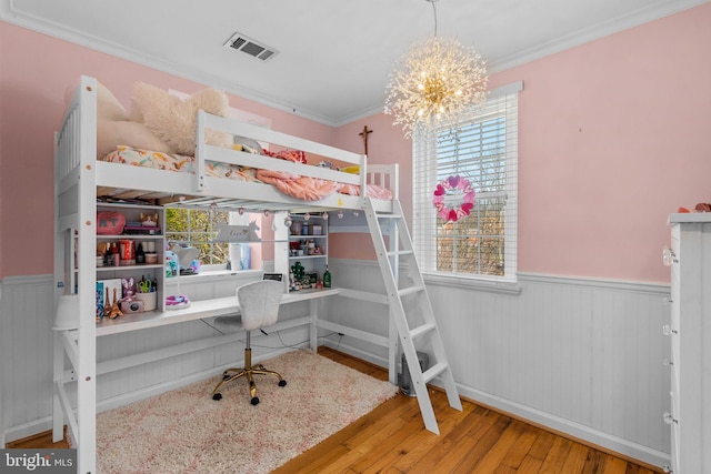 bedroom featuring visible vents, multiple windows, wood finished floors, and a wainscoted wall