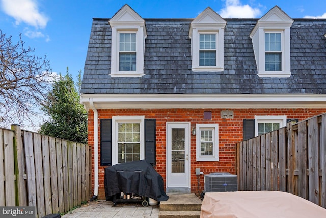 back of house with brick siding, central AC unit, and a fenced backyard