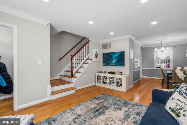 living room featuring visible vents, wood-type flooring, ornamental molding, and stairway