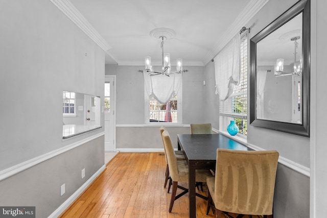 dining area with a notable chandelier, wood-type flooring, baseboards, and ornamental molding