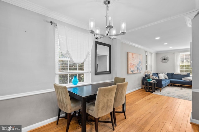 dining area featuring light wood finished floors, a notable chandelier, crown molding, and baseboards