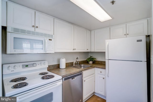 kitchen with a sink, white appliances, dark countertops, and white cabinets