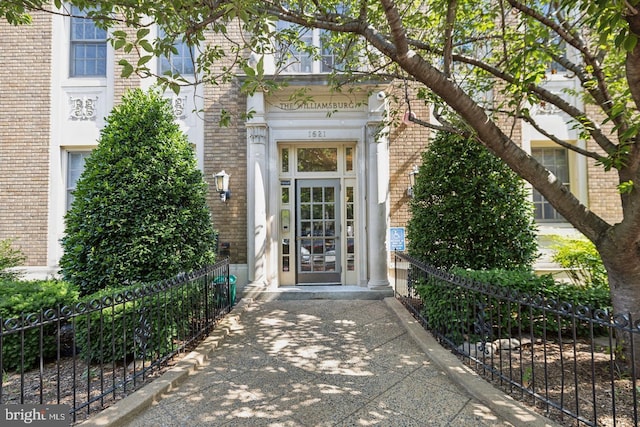 doorway to property featuring brick siding and fence