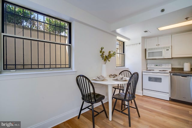 dining space featuring visible vents, baseboards, and light wood finished floors