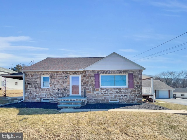 view of front of property with stone siding, an outdoor structure, a front lawn, and roof with shingles