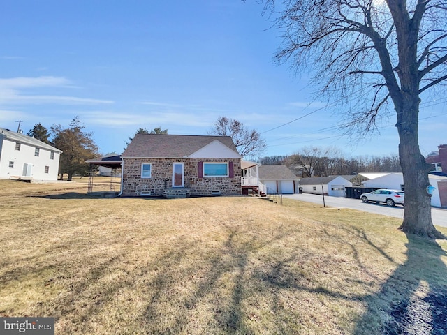 view of front of property with an outbuilding, brick siding, a detached garage, and a front lawn