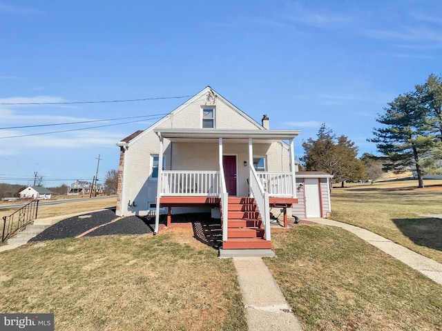 bungalow-style house featuring stairs, a front lawn, an outbuilding, and covered porch