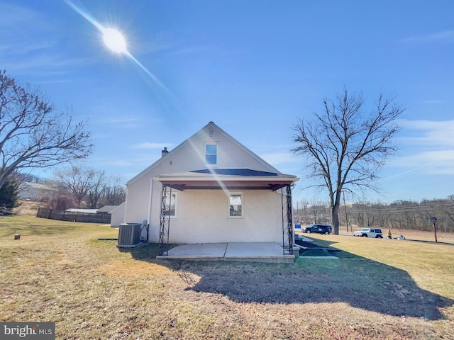 view of side of property with a yard, a patio, central AC unit, and stucco siding